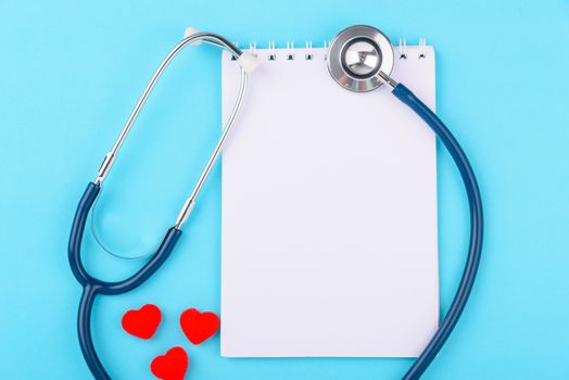 Doctor's Day concept, flat lay top view, stethoscope with peper note diagnosis of heart disease on blue background with copy space for text