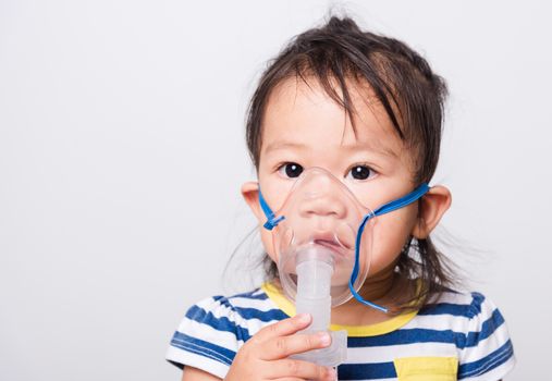 Closeup Asian face, Little baby girl sick her using steam inhaler nebulizer mask inhalation oneself on white background with copy space, health medical care