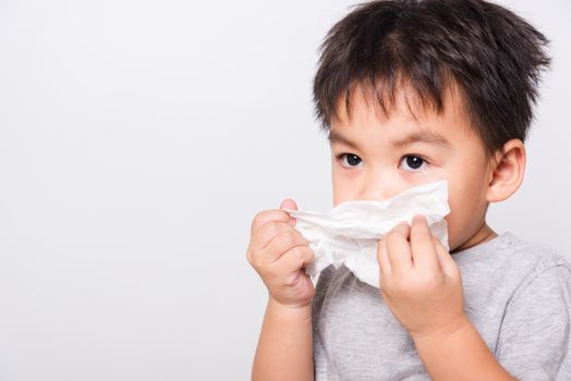 Closeup Asian face, Little children boy cleaning nose with tissue on white background with copy space, health medical care