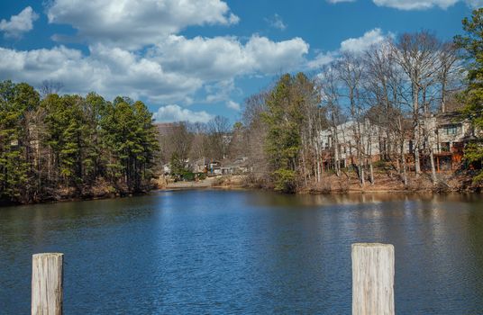 Homes around a small private blue lake beyond wood pilings