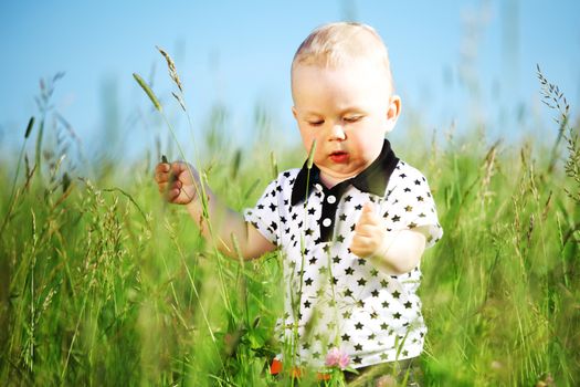 Cute baby boy walking in grass rural meadow