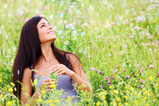 Happy woman smile in green grass soap bubbles around