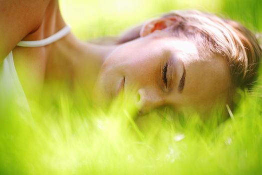 Beautiful young woman sleep on green spring grass