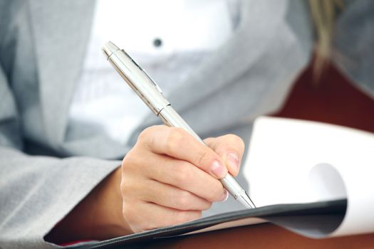 Business woman in suit writing notes with pen on document paper