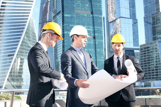 Team of architects comparing housing project with the building over skyscrapers background