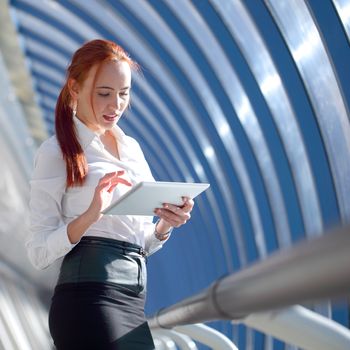Beautiful redhead young business woman using tablet pc in modern office building
