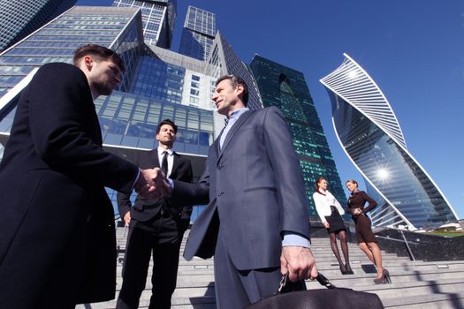 Business team shaking hands in agreement, finishing up a meeting outside office building