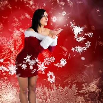 Pretty girl in santa outfit blowing against red snow flake pattern design