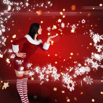 Pretty girl in santa outfit blowing against bright star pattern on red