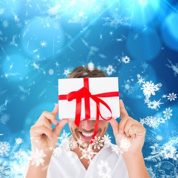 Man holding gift against blue snow flake pattern design