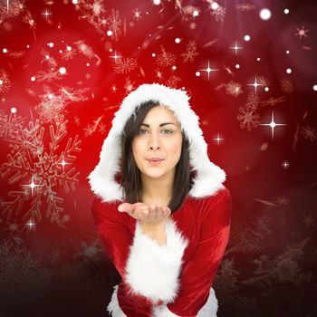 Pretty girl in santa outfit blowing against red snow flake pattern design