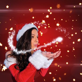 Pretty girl in santa outfit blowing against bright star pattern on red