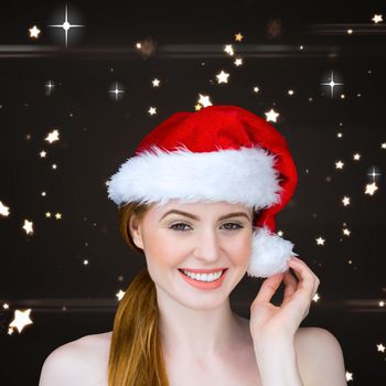 Pretty girl in santa costume smiling at camera against bright star pattern on black