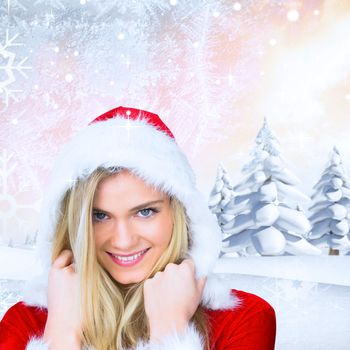 Pretty girl smiling in santa outfit against snowy landscape with fir trees