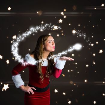 Sexy santa girl blowing a kiss against bright star pattern on black