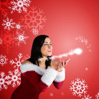 Pretty girl in santa outfit blowing against red snow flake pattern design