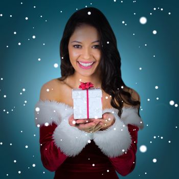 Pretty girl in santa outfit holding gift against blue vignette