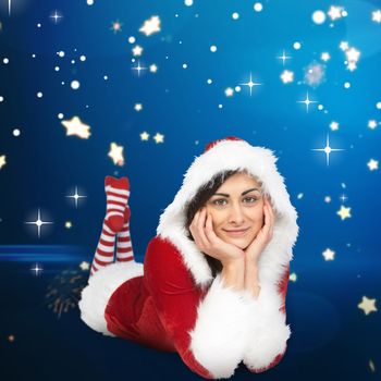 Pretty girl smiling in santa outfit against bright star pattern on blue