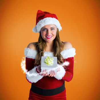 Pretty girl in santa costume holding gift box against orange vignette