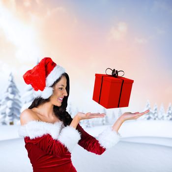 Pretty girl presenting in santa outfit against snowy landscape with fir trees