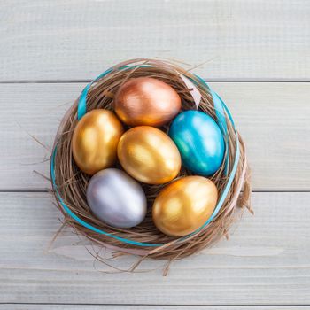 Beautiful Happy Easter holiday greeting banner with easter nest with colored eggs and decorated with ribbons over light wooden background with copy space for text