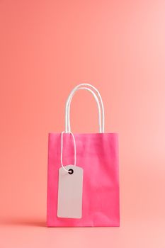 One pink shopping or gift bag with blank label tag isolated on pink background