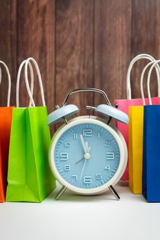 Blue alarm clock and colorful shopping bags for time to buy concept