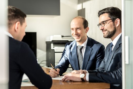 Team of confident successful business people reviewing and signing a contract to seal the deal at business meeting in modern corporate office. Business and entrepreneurship concept.