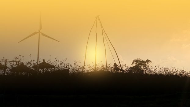 Child playing in a field at sunset with a windmill.