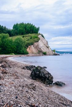 stone on the riverbank and cliff with birch woodland on background