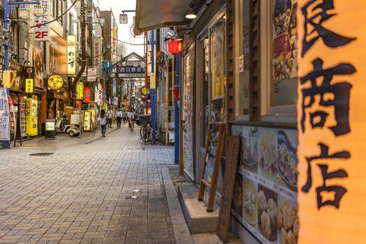 Traditional wooden lantern and blue metal entrance gate of the shopping street from the west exit of Kanda Station on the Yamanote Line. The street extends over 300 meters and has no less than 100 shops, restaurants or pachinko.