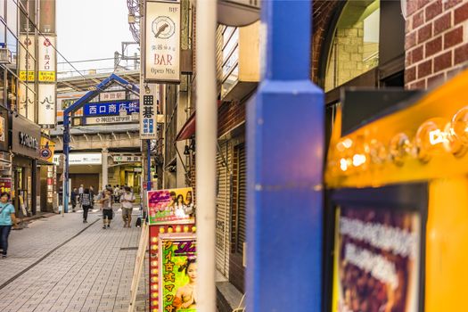 Blue metal entrance gate and neon signs in the shopping street from the west exit of Kanda Station on the Yamanote Line. The street extends over 300 meters and has no less than 100 shops.