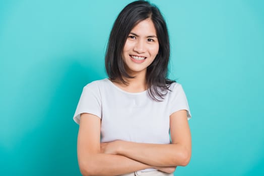 Portrait Asian beautiful happy young woman smile white teeth wear white t-shirt standing crossed arms, on a blue background with copy space