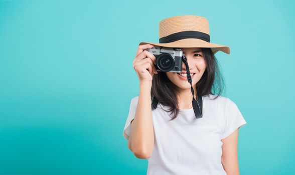 Traveler tourist happy Asian beautiful young woman smile in summer hat standing with mirrorless photo camera, shoot photo in studio on blue background with copy space for text