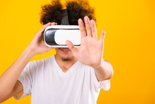 Asian handsome man with curly hair he using virtual reality headset or VR glass isolate on yellow background