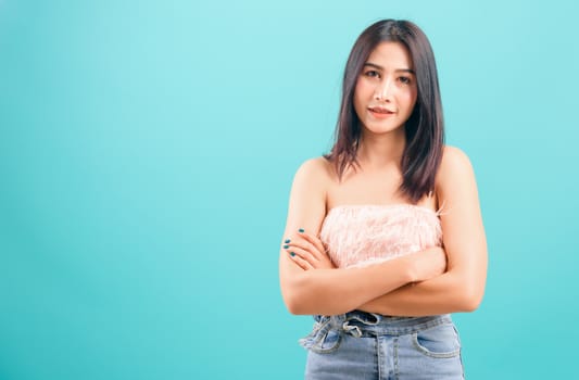 Smiling face asian beautiful woman her crossed arms looking to camera on blue background, with copy space for text