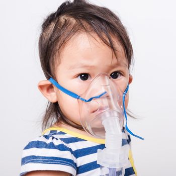 Closeup Asian face, Little baby girl sick her using steam inhaler nebulizer mask inhalation oneself on white background with copy space, health medical care