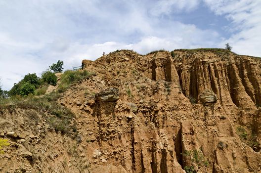 At close of the famous Stob Pyramids with unusual shape red and yellow rock formations, green bushes and trees around, west share of Rila mountain, Kyustendil region, Bulgaria, Europe