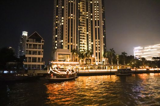 embankment at Chao Phraya River in Bangkok city. With two boats for trip. cityscape in the evening. Nigt life in asia