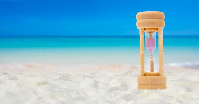 Hourglass set on a white sand background sea background, time concept