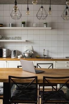 Close Up of laptop on kitchen counter with kitchen on background