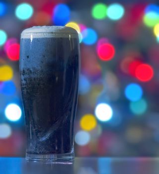 A Stouts with christmas lights on the background. Guinness dark Irish dry stout