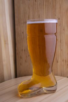 Beer in boot beer glass on a wooden board in wooden background