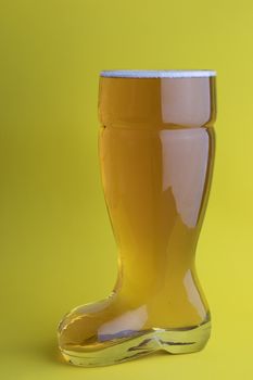 Beer in a boot beer glass in yellow background