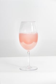 A cup of rose wine on a white table and background
