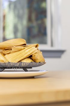 Half view on a vertical view of fresh tamales on a wooden table, traditional Mexican food.