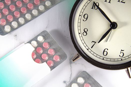 Birth control pills with a clock and a marble background