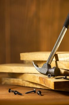 Hammer and screw on lumber in lighting and shadow of the sunshine in morning. The concept of woodcraft or carpentry.