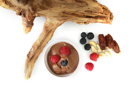 Fruit and mousse on flat wood and white background. A breakfast ready to be served, Raw and organic food with a piece of wood as decoration