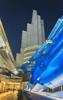 Futuristic architecture with mirroring and transparent blue plastic panels swiveling in Shibuya district in Dogenzaka street leading to Shibuya Crossing Intersection in front of Shibuya Station in a summer evening.